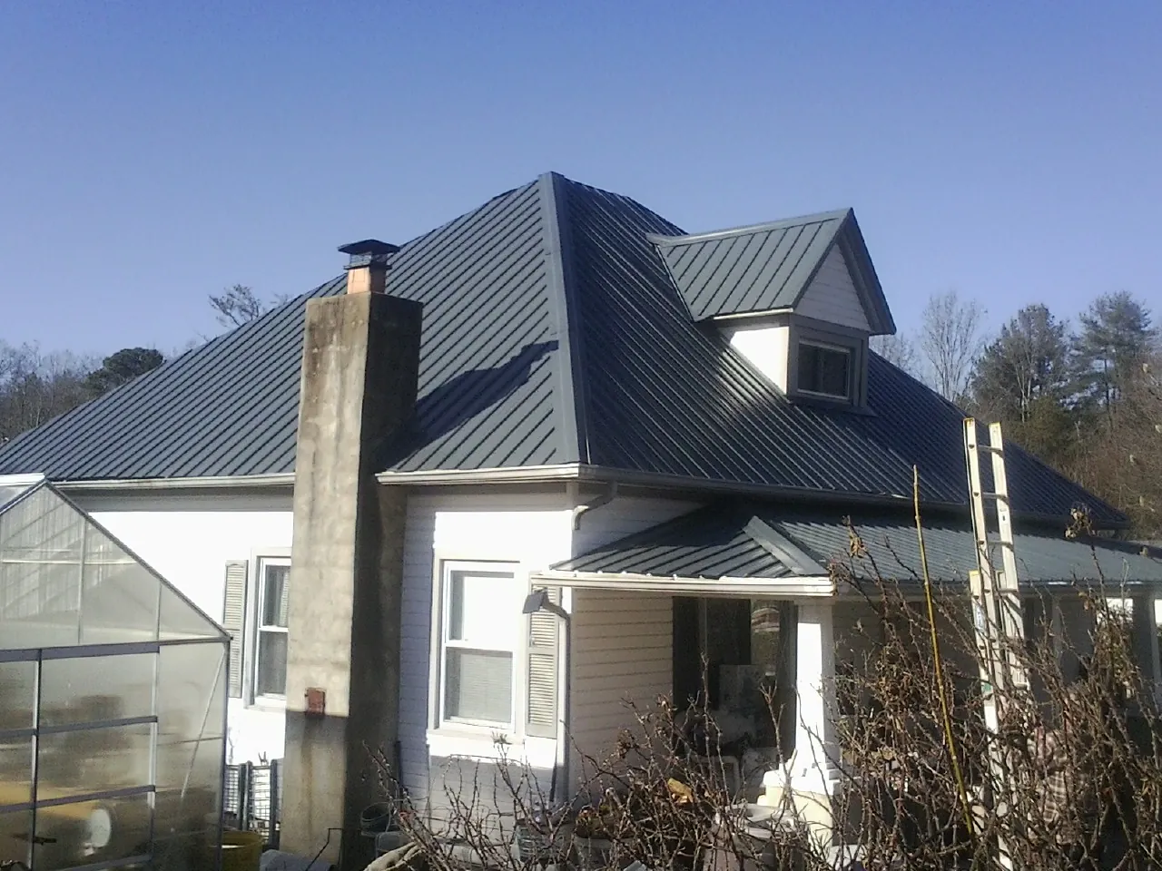 Dark blue standing seam metal roof on a white farmhouse with dormer — Slate & Tile Roof Repair by Roofing Brothers in Halfway