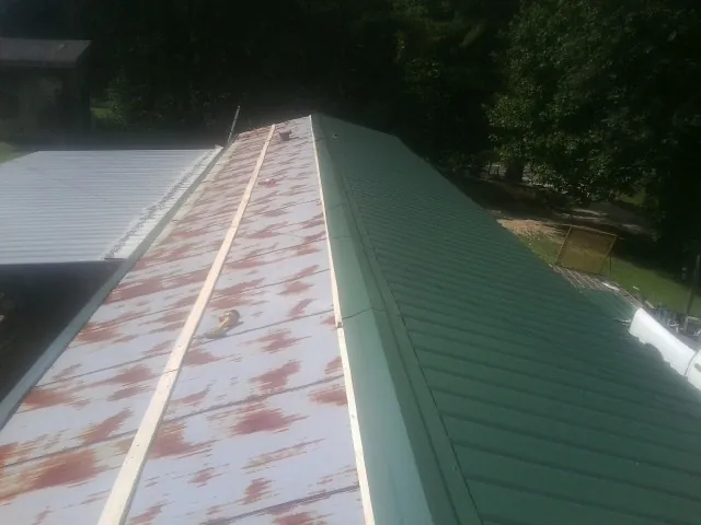 Old rusted panels beside newly installed green metal roofing — Wind Damage Roof Repair by Roofing Brothers in Halfway