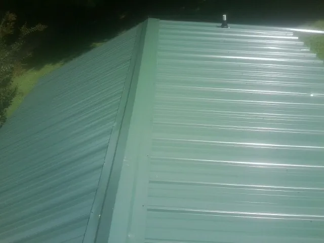 New green metal panels meeting at the ridge of a roof — Flat Roof Repair work by our crew in Halfway