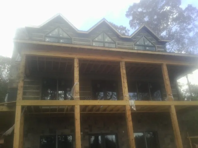 Dormers and porch framing on a large log home under construction — Roof Coating work by our crew in Halfway