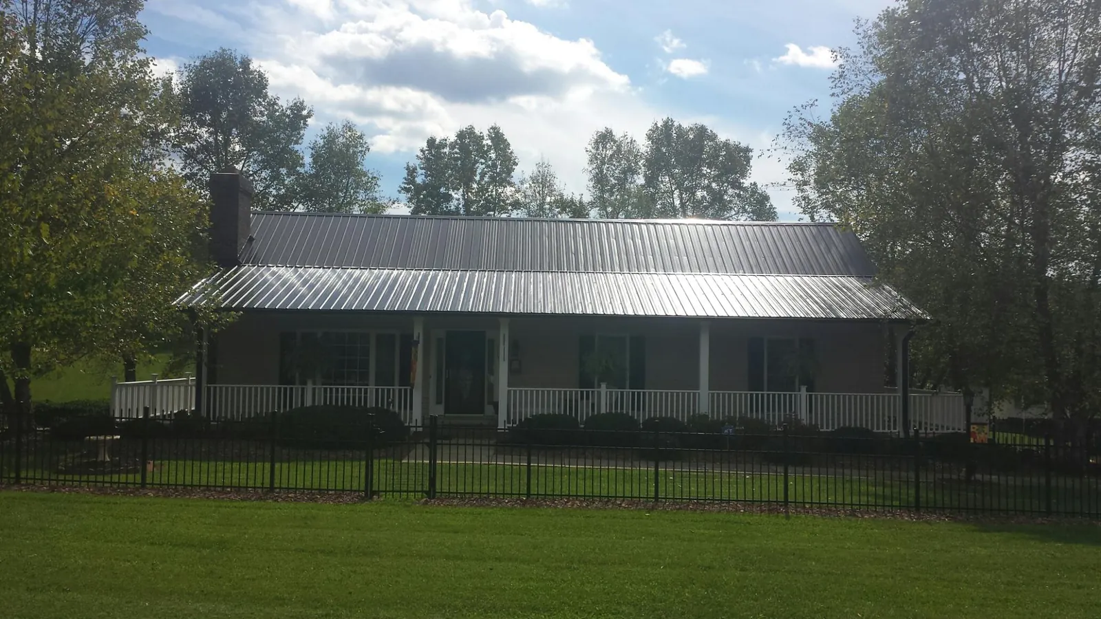 Gray metal roof on a brick ranch with a full width front porch — Gutter Guard Installation work by our crew in Halfway