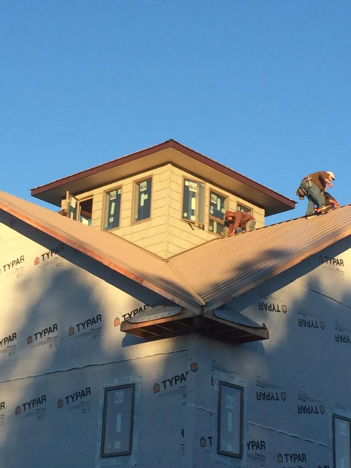Roofers working around a rooftop cupola on a new metal roof at sunset — Roof Waterproofing in Halfway by Roofing Brothers
